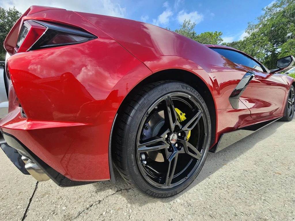 Red car with a black wheel, photographed outdoors